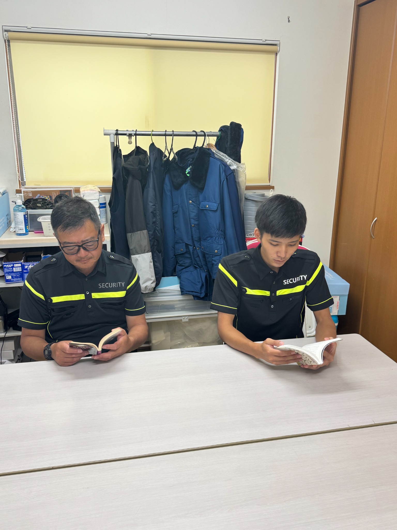 富士警備保障の事務所で本を読む二人の社員
