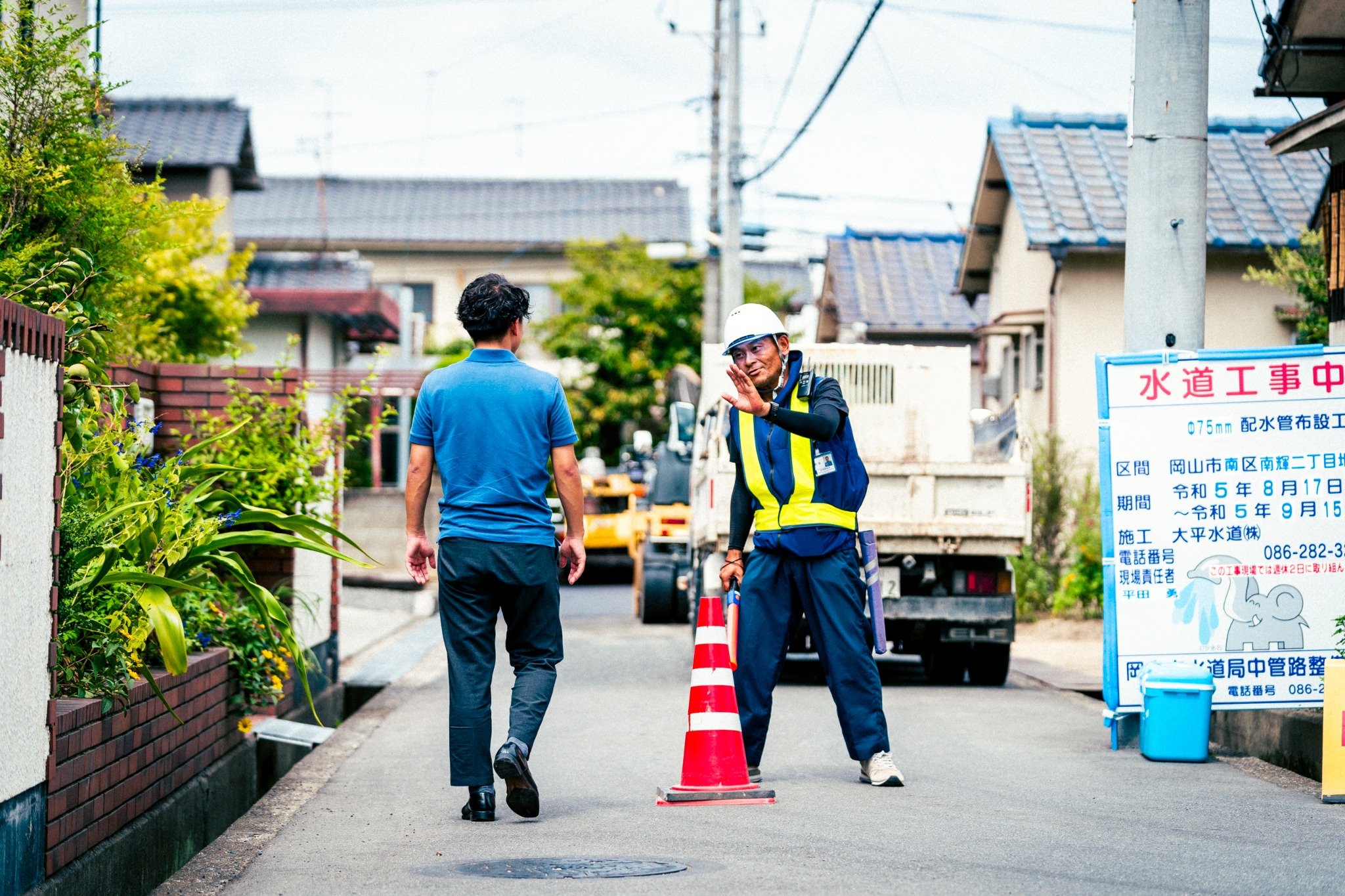 住宅街の工事現場で歩行者を誘導する富士警備保障株式会社の警備員