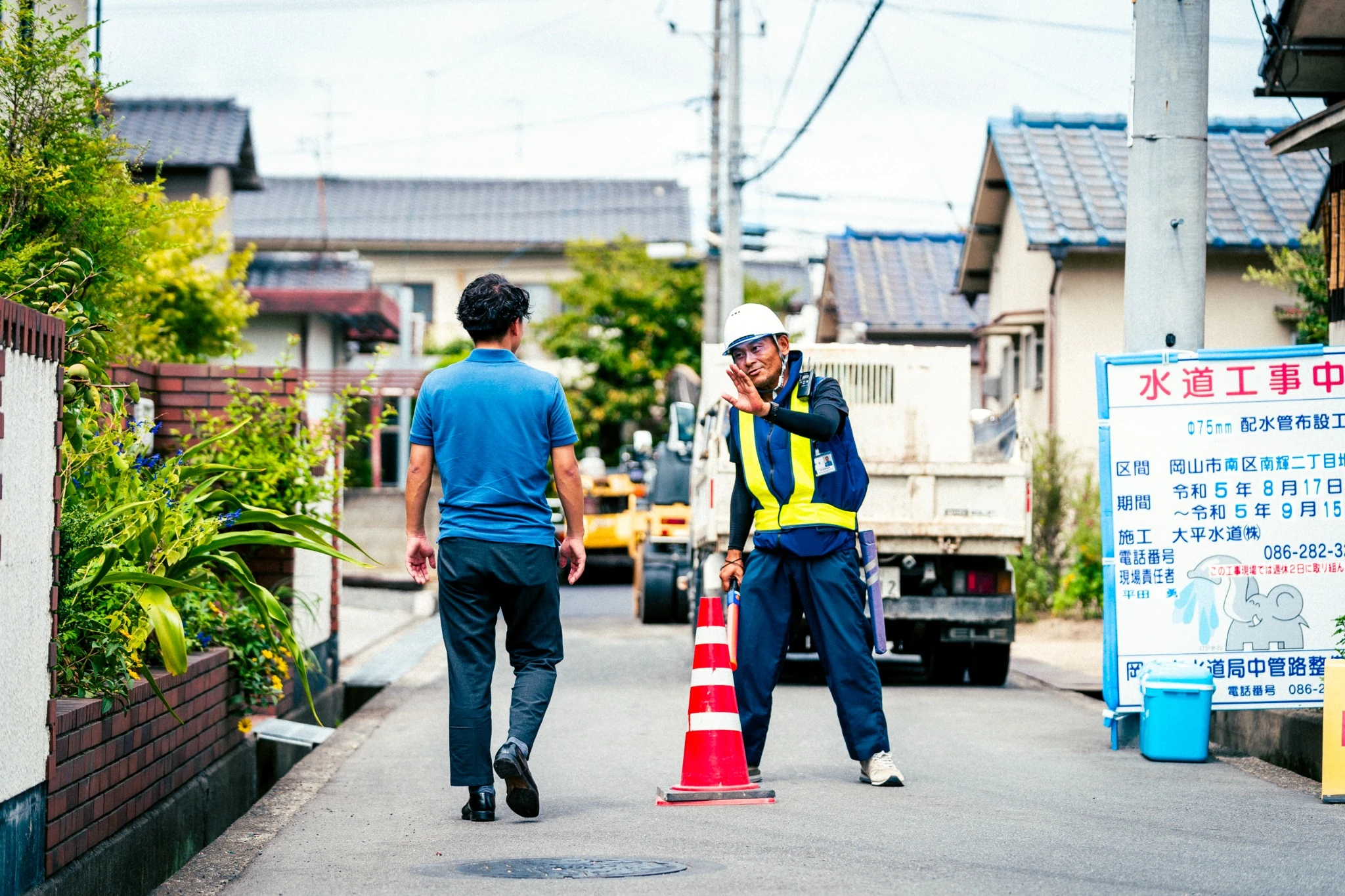 住宅街の工事現場で歩行者を安全に誘導する富士警備保障株式会社の隊員