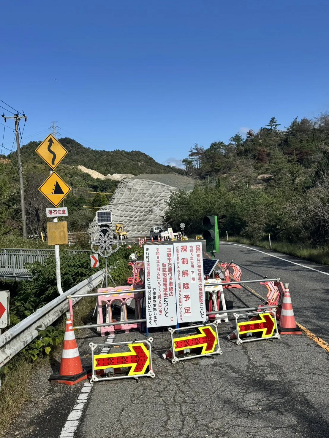 カーブ区間手前の規制案内、信号機、矢印板と金甲山の法面