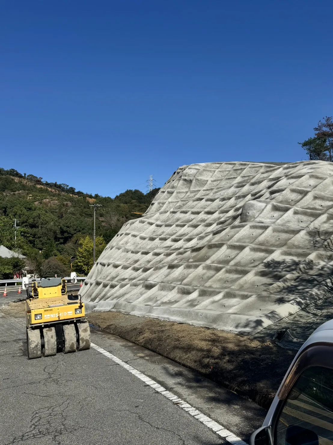 金甲山の法面工事の終盤、道路沿いに広がる法面と作業区間