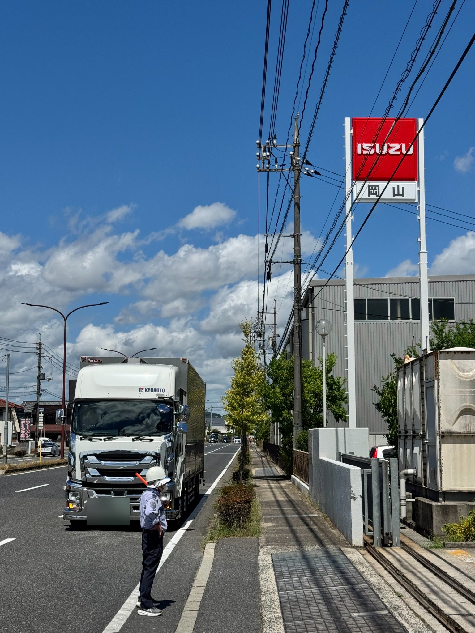 大型車両点検修理拠点で入出庫誘導を行う富士警備保障株式会社の警備員