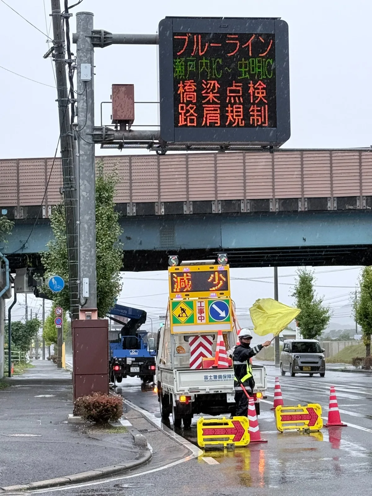 大雨の西大寺・五明跨道橋で旗による交通誘導を行う隊員